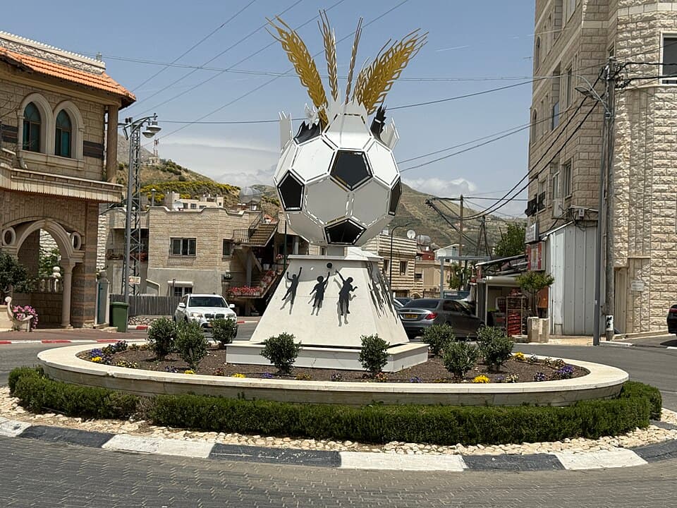 Name: Shams Tower - the monument in memory of the 12 chi Description: A monument shaped like a soccer ball, placed on a dedicated pedestal, in the square next to the soccer field w