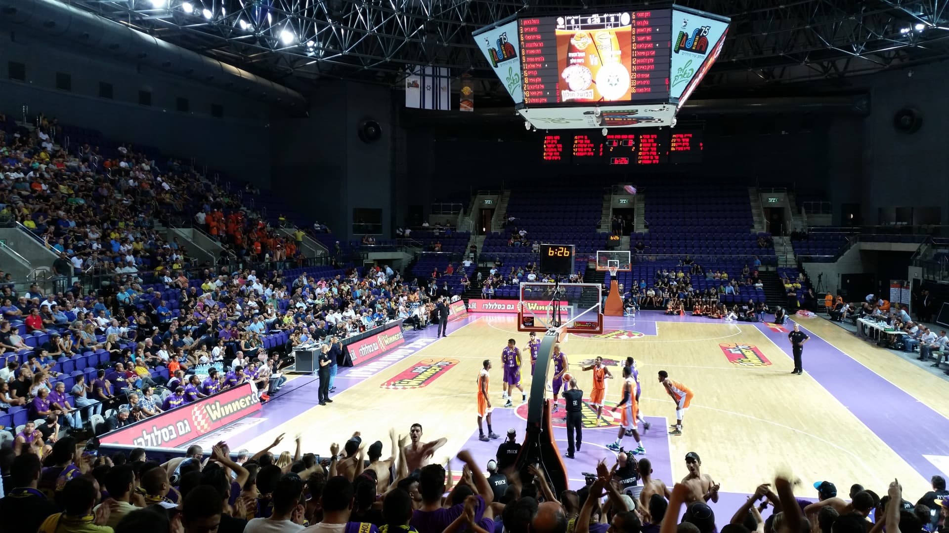 Hapoel Holon players in purple during a basketball game at Toto Arena