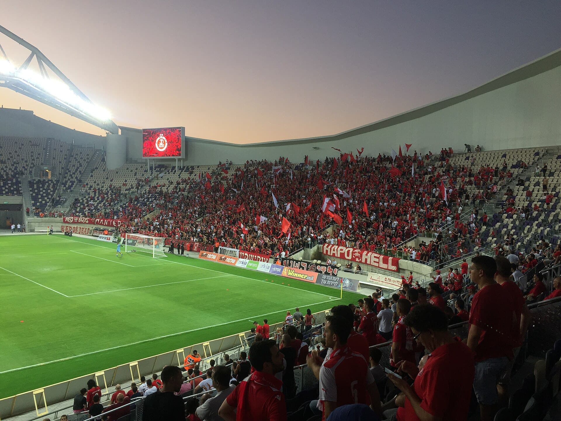 Hapoel Tel Aviv supporters dressed in red fill their stand at Bloomfield Stadium