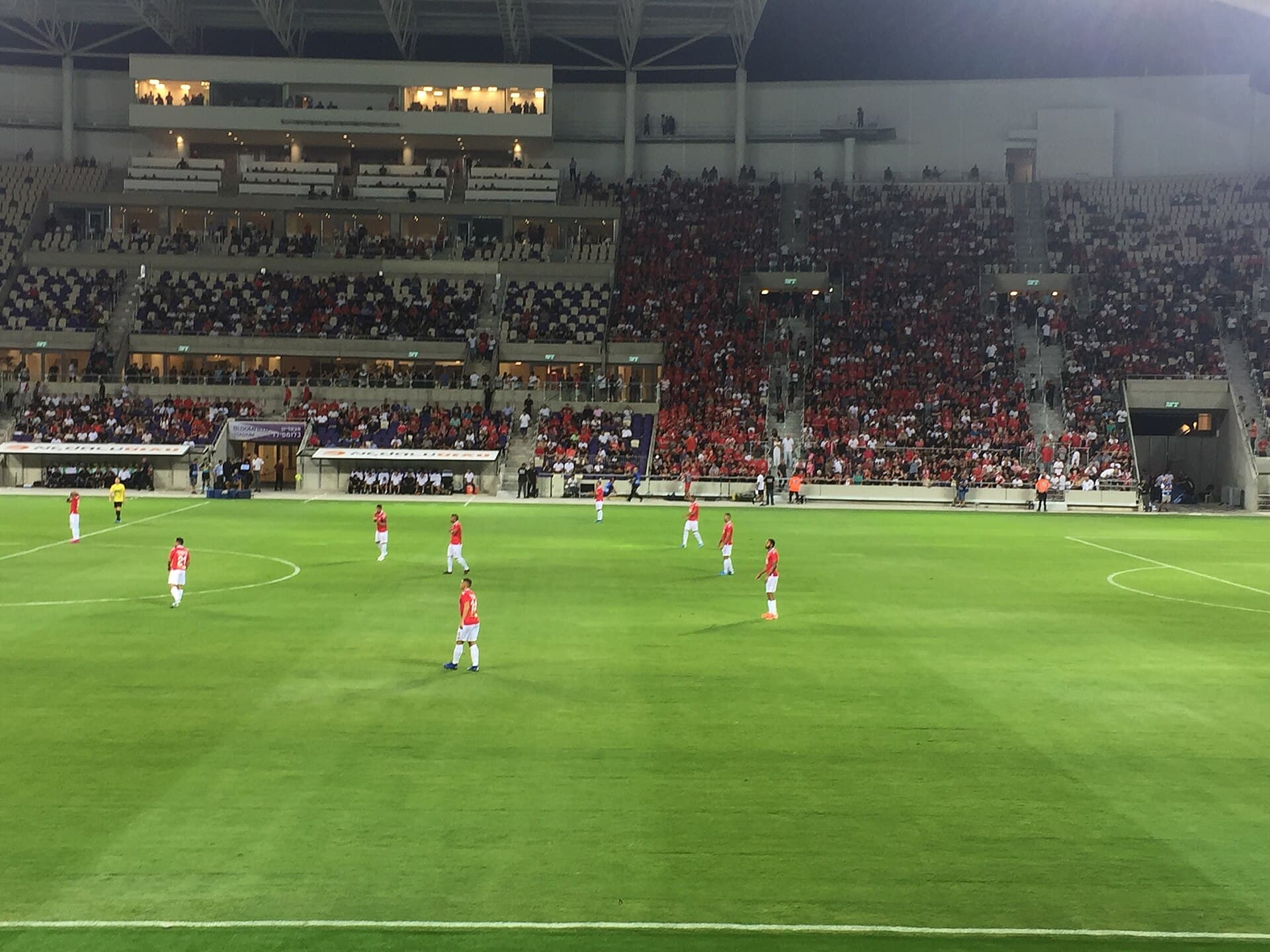 Hapoel Tel Aviv players in red spread across the pitch at Bloomfield Stadium