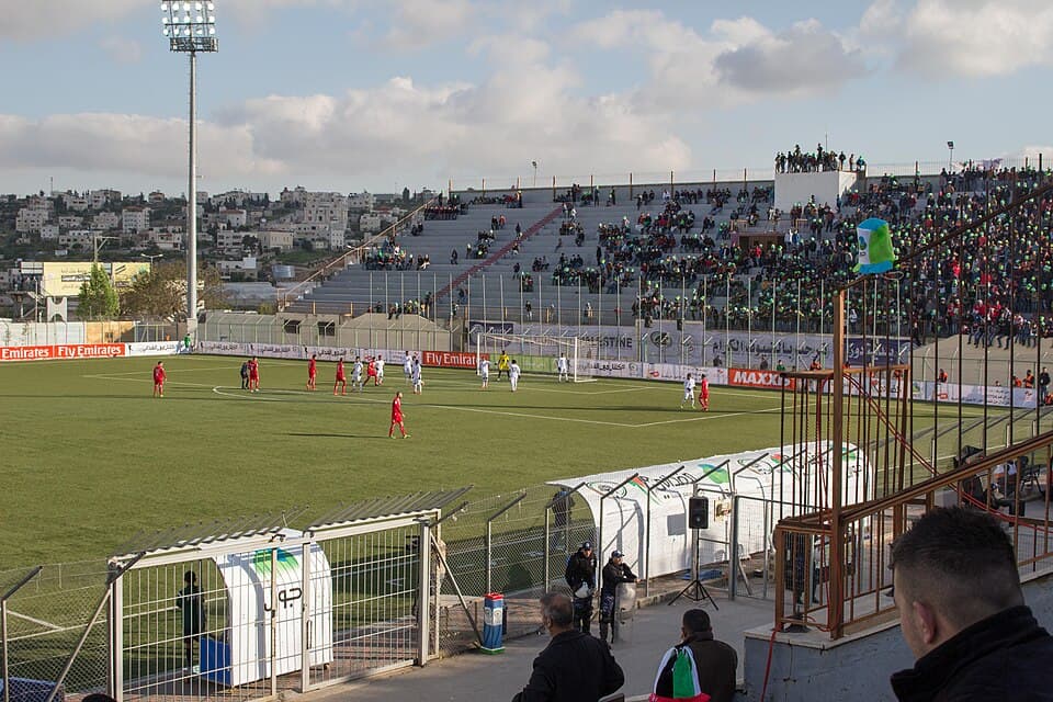 A crowd watches Palestine and East Timor play a World Cup Qualifier match at Dora Stadium, Hebron