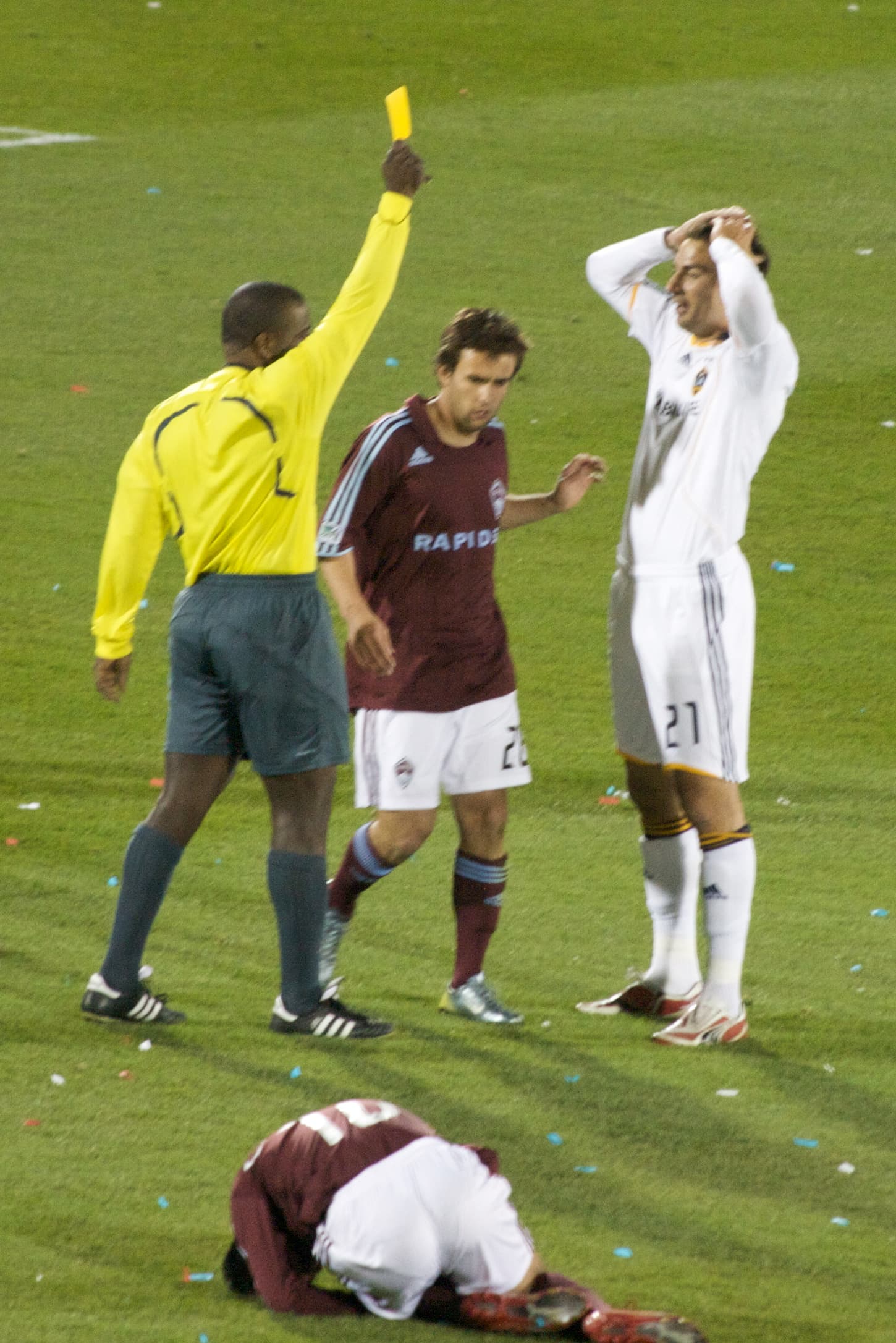 A football referee raises a yellow card during a match