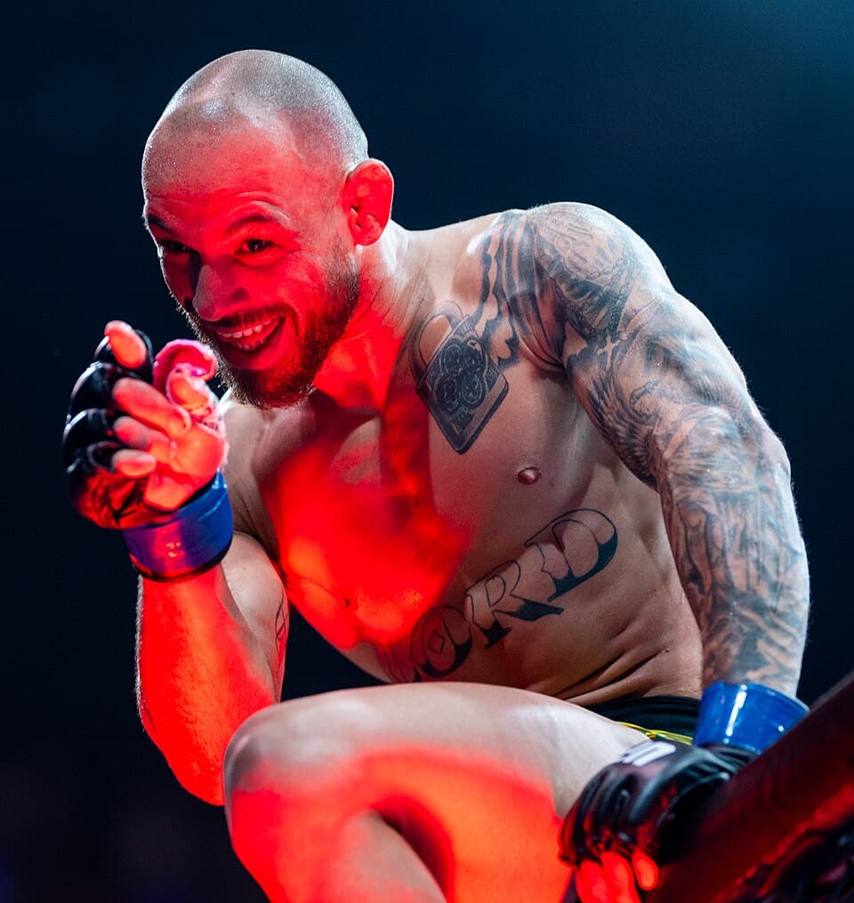 UFC featherweight Jean Silva gestures in the octagon under red lights