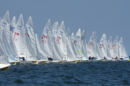 A fleet of 470 dinghies crosses the start line of a race
