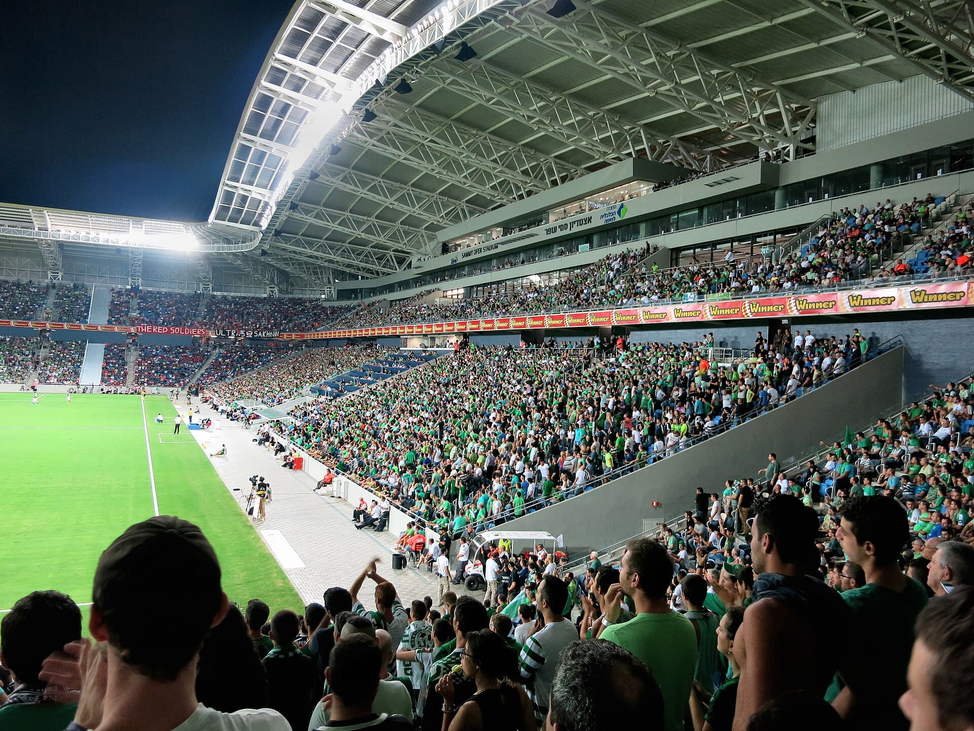 Maccabi Haifa supporters dressed in green fill the western stand at Sammy Ofer Stadium